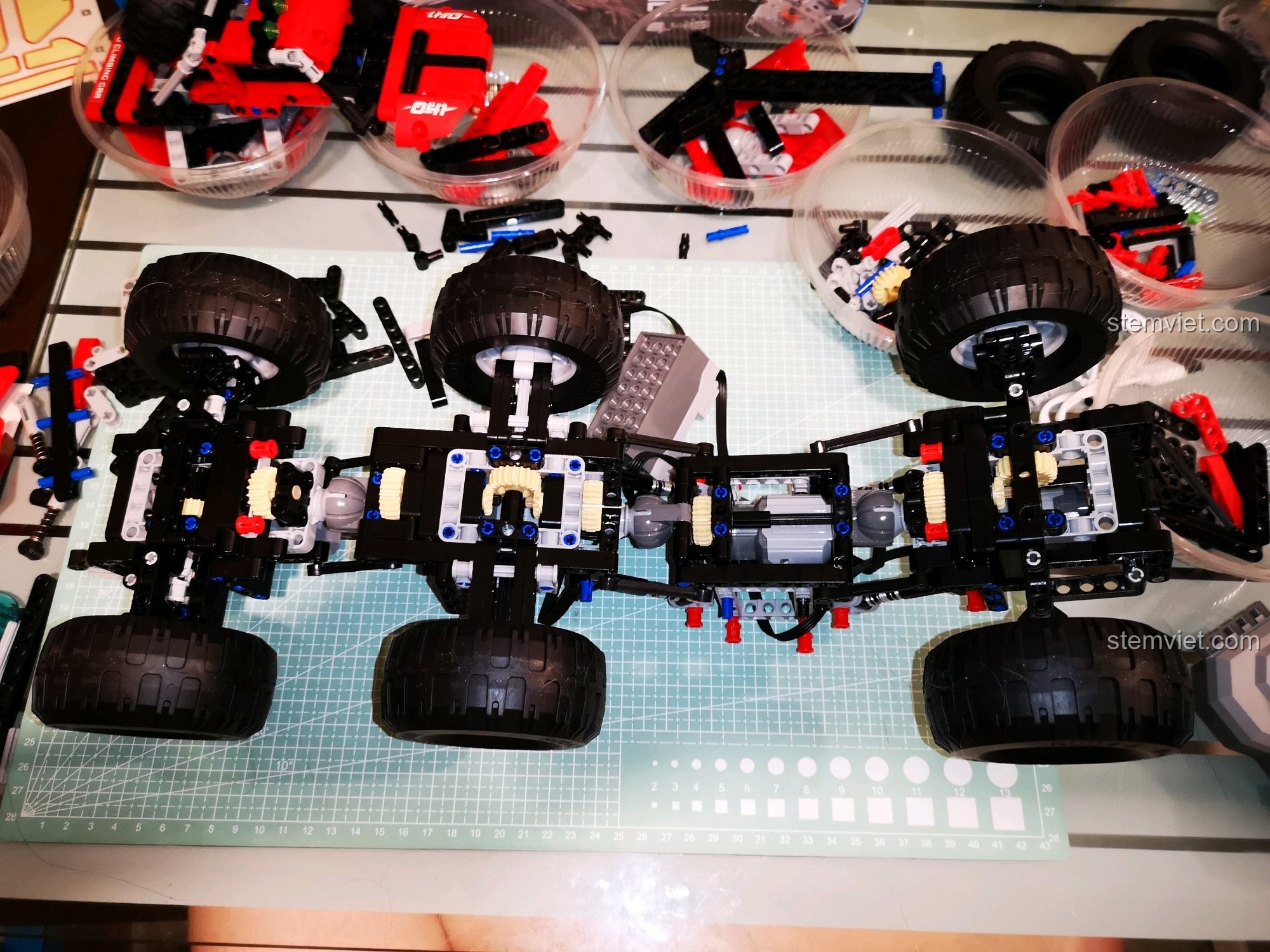 Cận cảnh khung gầm xe địa hình CaDA C51041 MOC 6x6 với ba trục bánh xe rõ ràng, cho thấy cấu trúc chắc chắn và phức tạp. Đánh giá CaDA 51041 Xe Off-Road RC.