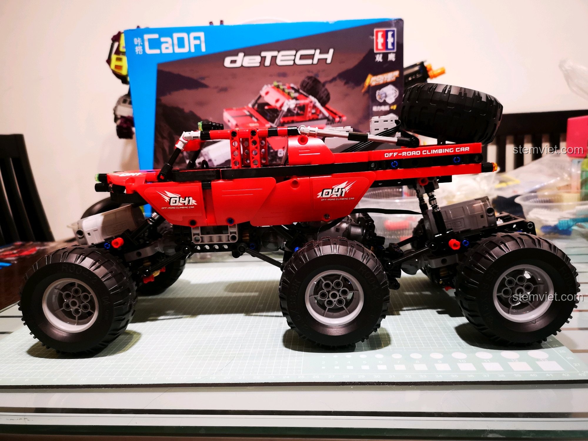 Xe địa hình CaDA C51041 MOC 6x6 hoàn thiện đặt cạnh hộp sản phẩm, cho thấy sự khác biệt rõ rệt giữa bản gốc và bản độ. Review CaDA C51041 Xe Leo Núi Địa Hình.