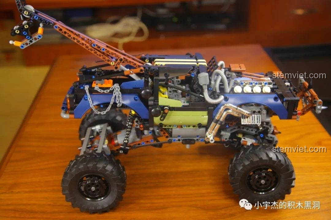 Mô hình Mould King 18006 Xe Tải Kéo Nổi Loạn Hậu Tận Thế trên giá đỡ, thể hiện hệ thống treo và khoảng sáng gầm.