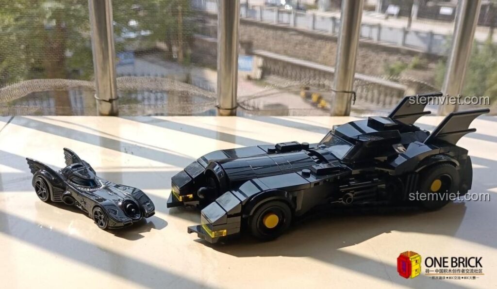 Mô hình Batmobile Mould King 27018 đã lắp ráp hoàn chỉnh, đặt cạnh một mô hình nhỏ hơn, thể hiện sự khác biệt kích thước ấn tượng.