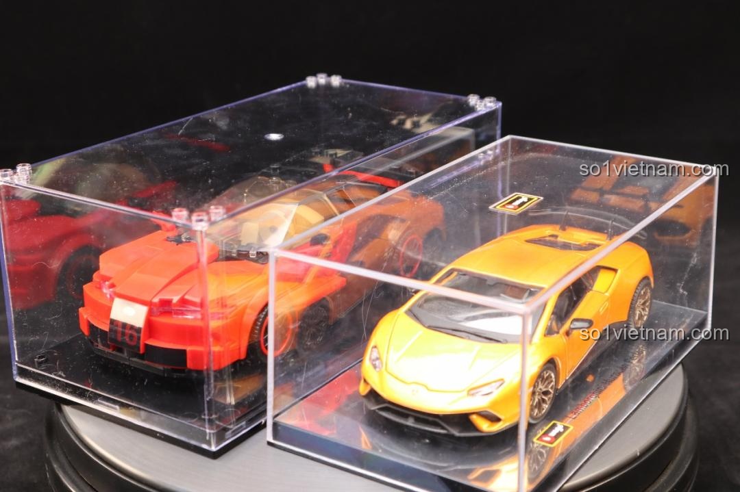 Mô hình Bugatti Veyron Mould King 27027 trong hộp mica, đặt phía trên một mô hình xe khác màu đỏ.