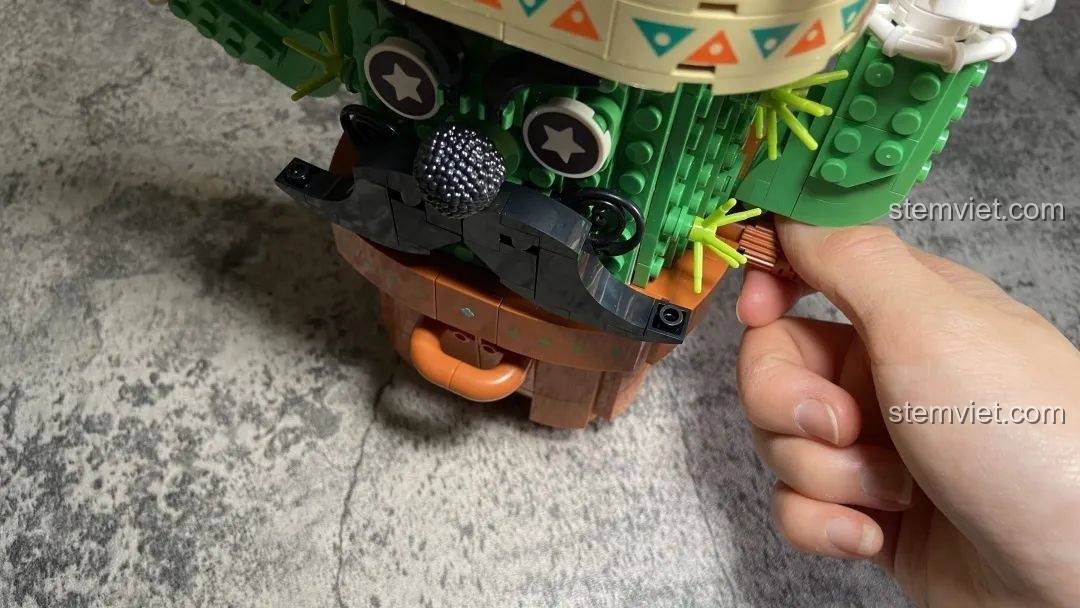 Bàn tay đang vặn nút để lấy trứng gashapon từ đồ chơi mô hình Máy Vặn Trứng Xương Rồng Mexico Pantasy 61007, thể hiện tính năng tương tác.