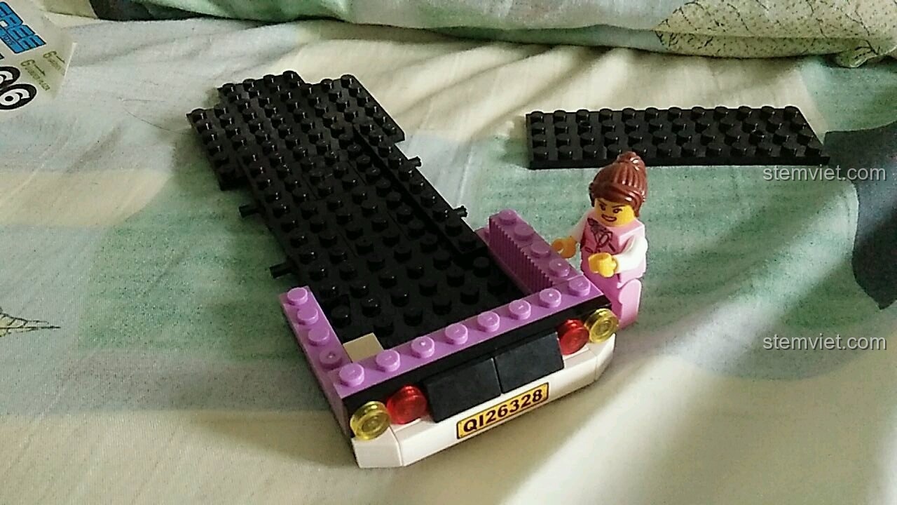 Minifigure hướng dẫn viên du lịch đang kiểm tra phần khung gầm dài của xe buýt QMAN 1123.