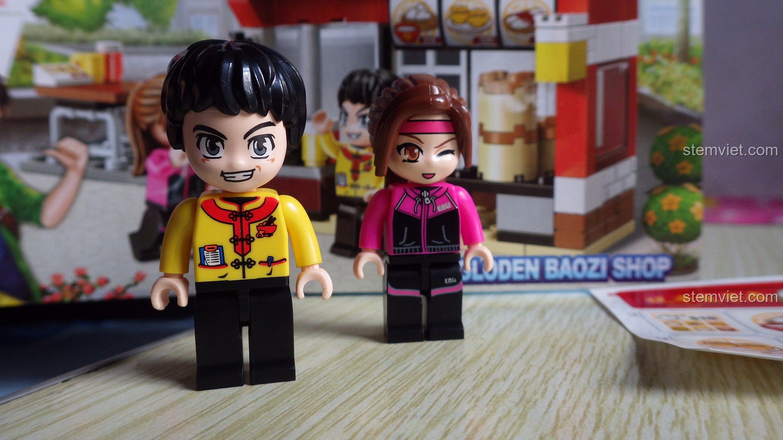 Hai nhân vật A Long và Nana trong bộ lắp ráp QMAN 1132 Tiệm Bánh Bao Yuezao, với thiết kế đầu to đặc trưng.