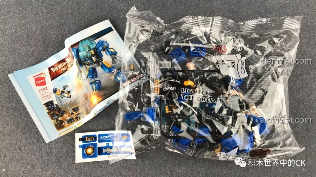 Mở hộp bộ đồ chơi lắp ráp QMAN 2702 Người Máy Khổng Lồ, bao gồm sách hướng dẫn, túi mảnh ghép và sticker.