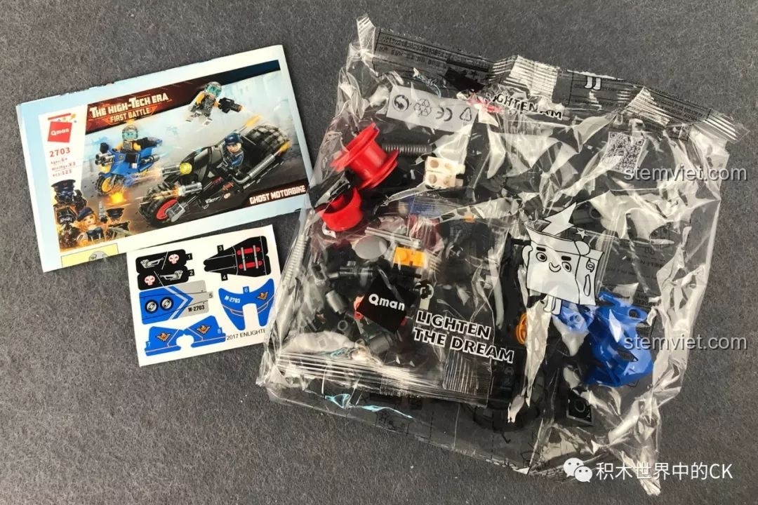 Mở hộp bộ đồ chơi lắp ráp QMAN 2703 Xe Chiến Đấu U Linh, bao gồm sách hướng dẫn, túi mảnh ghép và sticker.