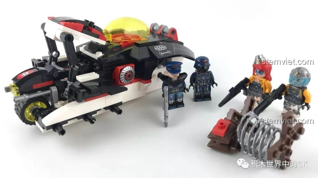 Quá trình lắp ráp bộ đồ chơi QMAN 2715 Pháo Laser tự hành đang diễn ra, hình dáng xe dần hiện rõ với các minifigure đứng cạnh.