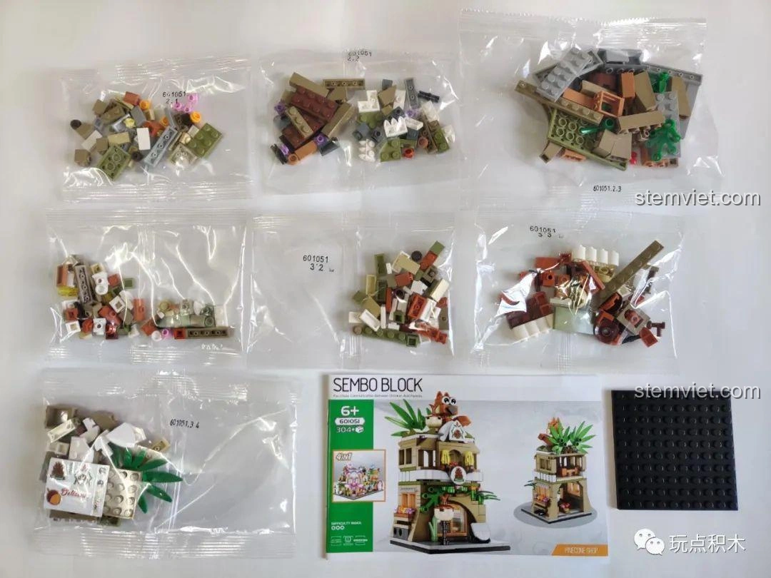 Toàn bộ linh kiện bên trong hộp Bộ Lắp Ghép Phố Mini Sembo Block 601051, bao gồm các túi mảnh ghép, sách hướng dẫn và đế lắp.