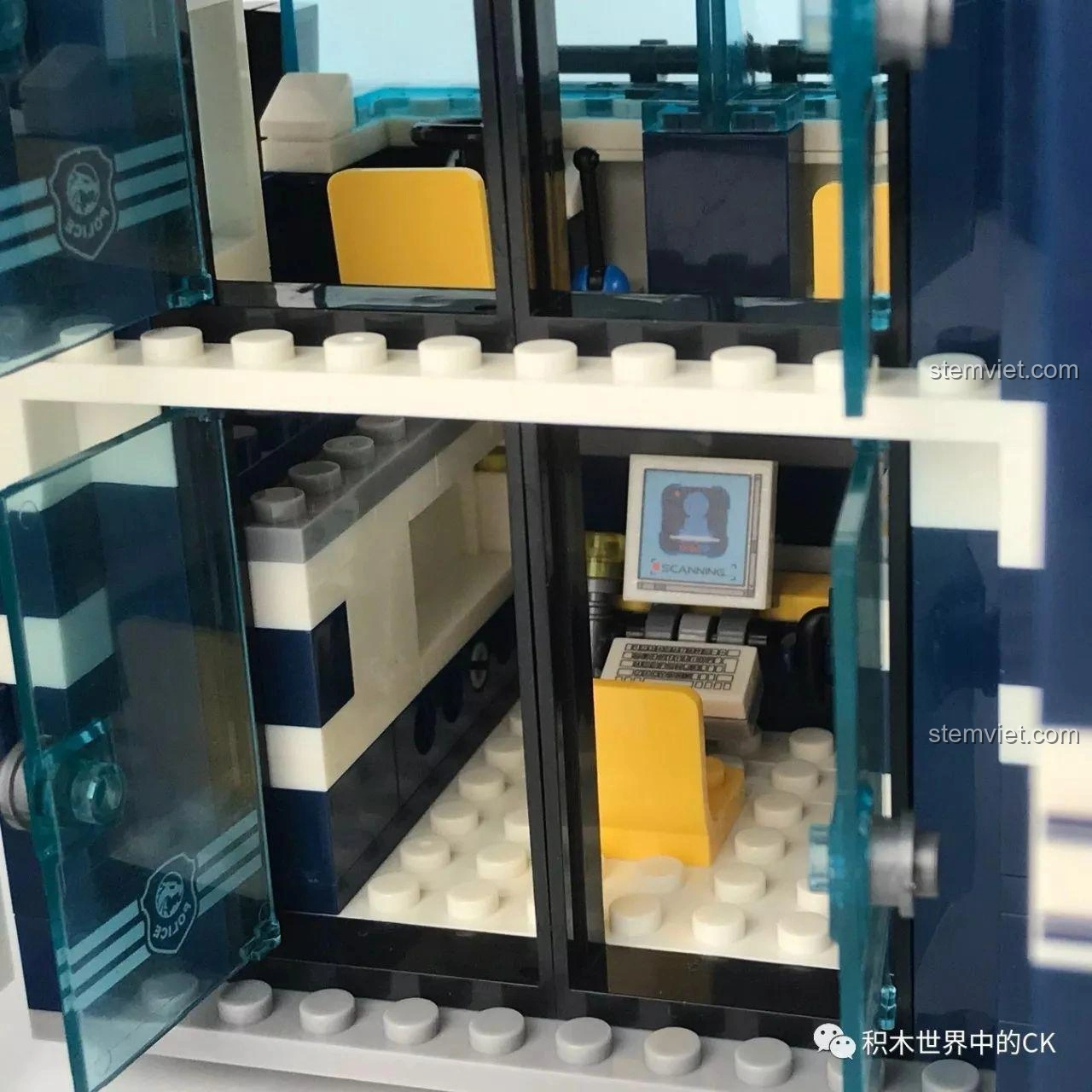 Phòng thẩm vấn bên trong trạm giam di động Sembo SD9816, với cửa song sắt và bảng hiệu 'INQUEST ROOM'.