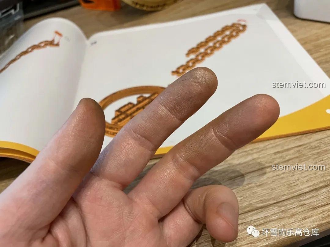 Bàn tay bị dính bụi màu vàng sau khi lắp các chi tiết mạ vàng của bộ Sembo 707901C, cho thấy lớp phủ có thể bị bong nhẹ.