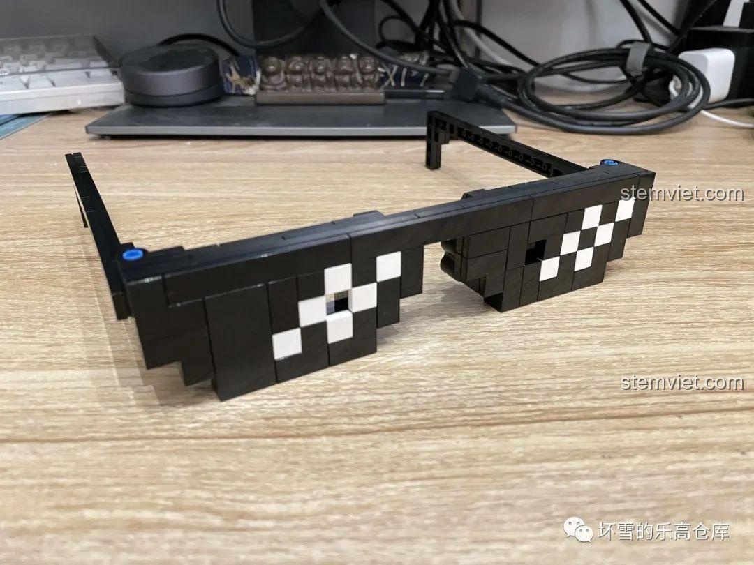 Chiếc kính pixel màu đen đã lắp xong từ bộ Sembo 707901C, đặt trên bàn gỗ, với các chi tiết trắng tạo hiệu ứng phản chiếu.