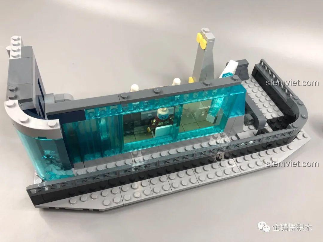 Góc nhìn từ bên ngoài vào sảnh tiếp khách tầng hai của bộ lắp ghép Tòa Tháp Avengers Taige 55120, với cửa sổ trong suốt màu xanh.