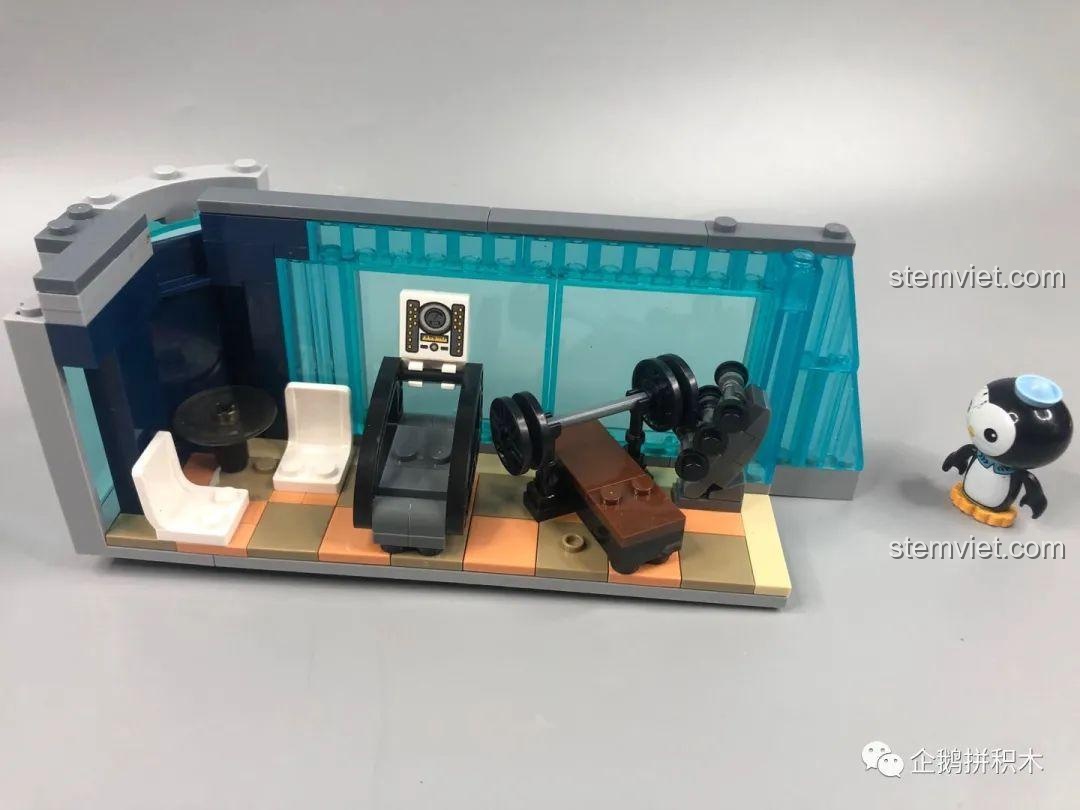 Mặt ngoài phòng gym của bộ đồ chơi Tòa Tháp Avengers Taige 55120, với các cửa sổ trong suốt màu xanh dương.