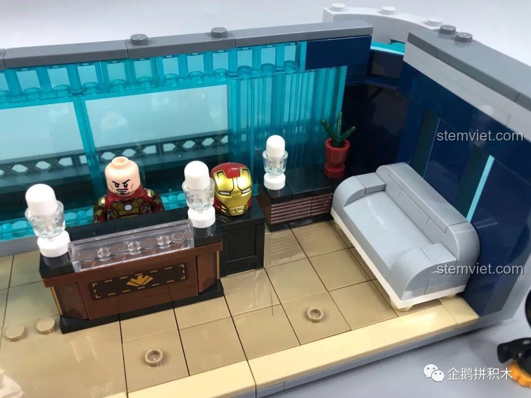 Cận cảnh quầy lễ tân trong sảnh tiếp khách tầng hai của Tòa Tháp Avengers Taige 55120, có tượng Iron Man và màn hình.