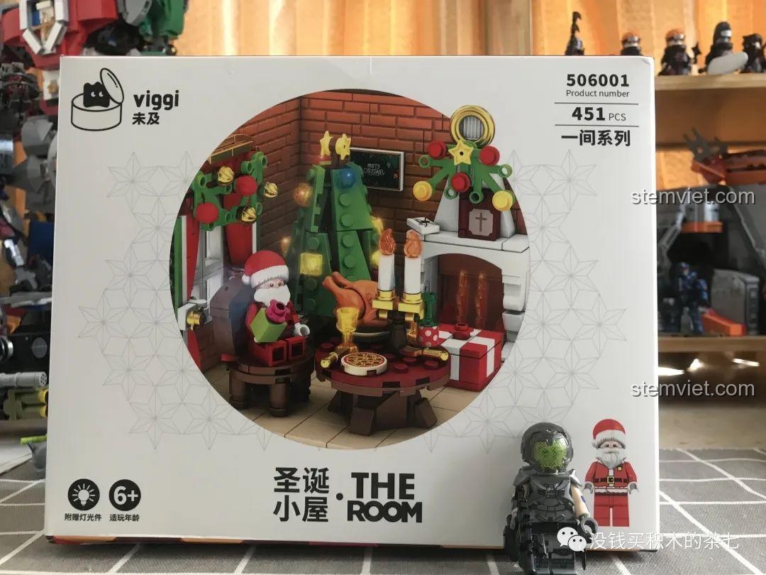 Hộp bộ lắp ráp Wekki 506001 Ngôi Nhà Giáng Sinh đặt cạnh một minifigure khác để so sánh kích thước.