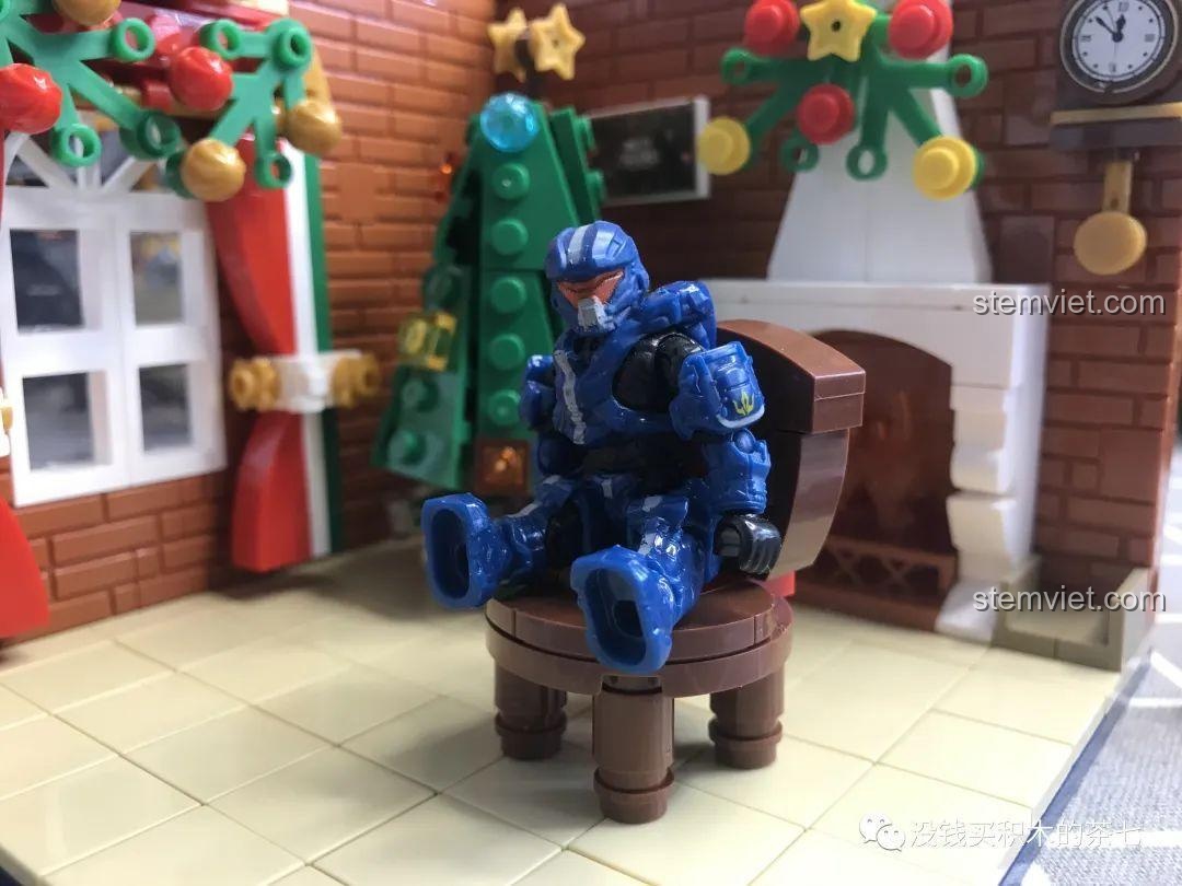 Minifigure khác ngồi thử ghế gỗ trong bộ lắp ráp Wekki 506001 Ngôi Nhà Giáng Sinh, cho thấy độ tương thích.