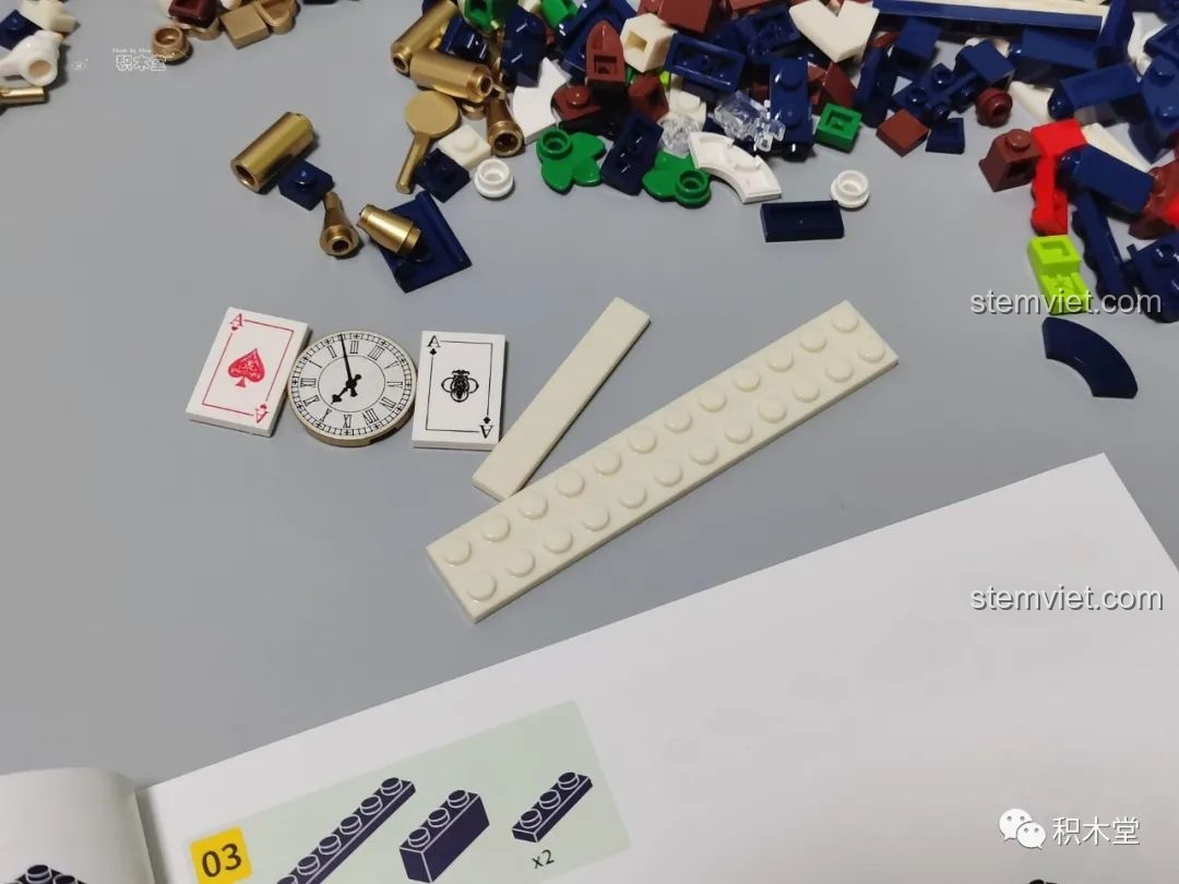 Các mảnh ghép in hình đồng hồ và quân bài, cùng các mảnh màu trắng ngà đặc trưng của bộ lắp ráp Wekki 506172 Sách truyện Alice ở xứ sở thần tiên.