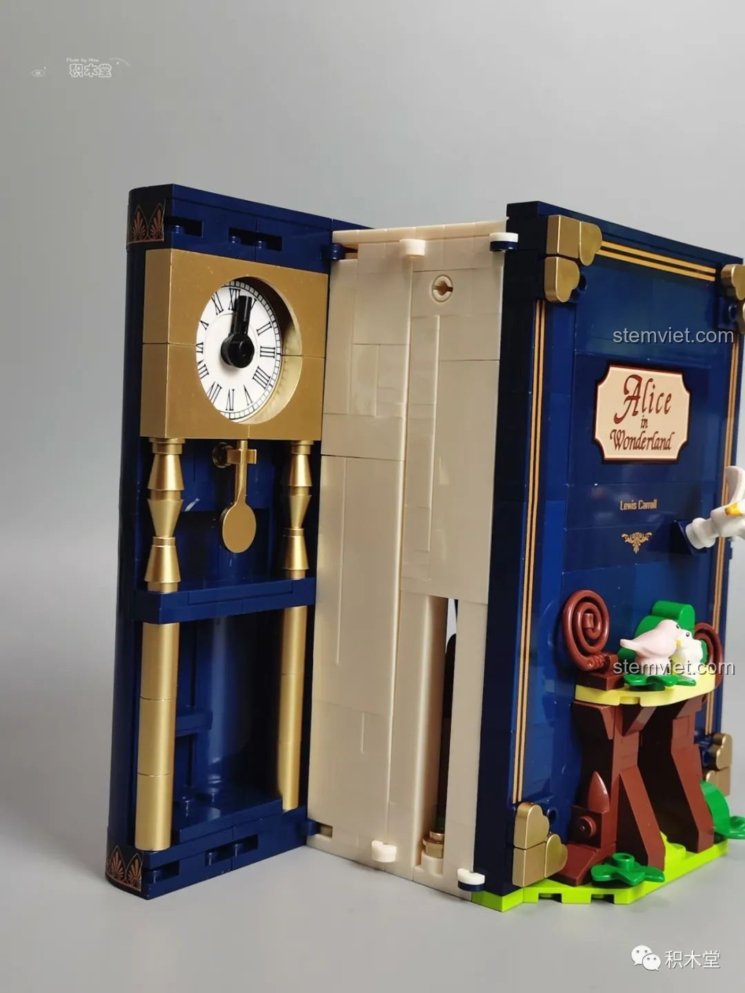 Một bên của mô hình sách Wekki 506172 Sách truyện Alice ở xứ sở thần tiên khi mở ra, hiển thị chi tiết đồng hồ quả lắc.