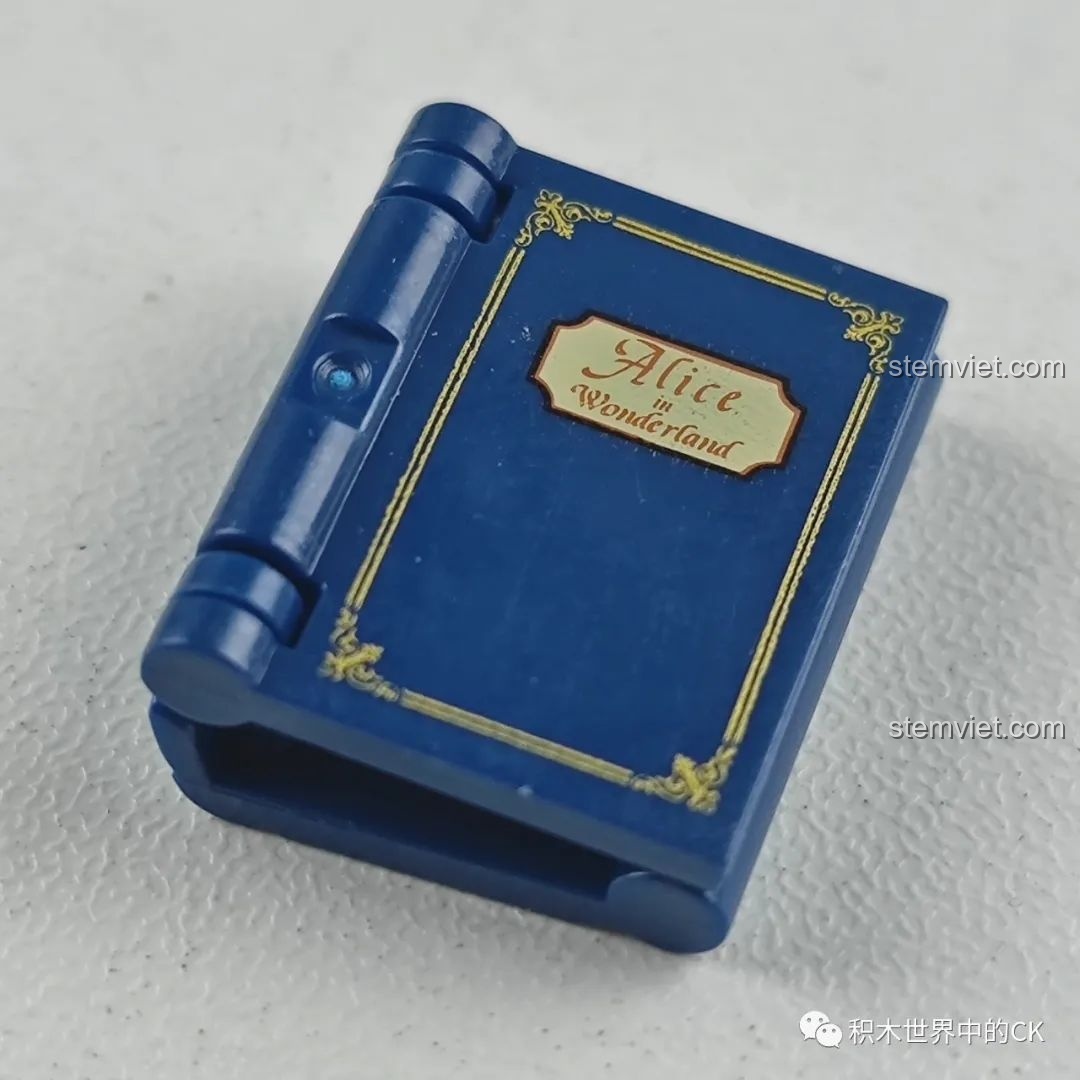 Mô hình cuốn sách nhỏ màu xanh dương với dòng chữ 'Alice in Wonderland' trên bìa, một chi tiết của bộ Wekki 506172.