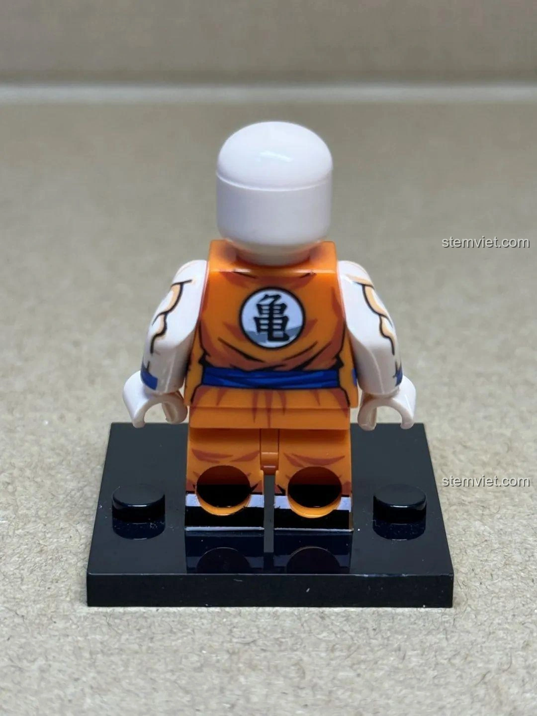 Mặt sau của minifigure Krillin trong bộ WM6180 Dragon Ball Z, cho thấy logo rùa trên lưng áo và chi tiết đai lưng màu xanh.