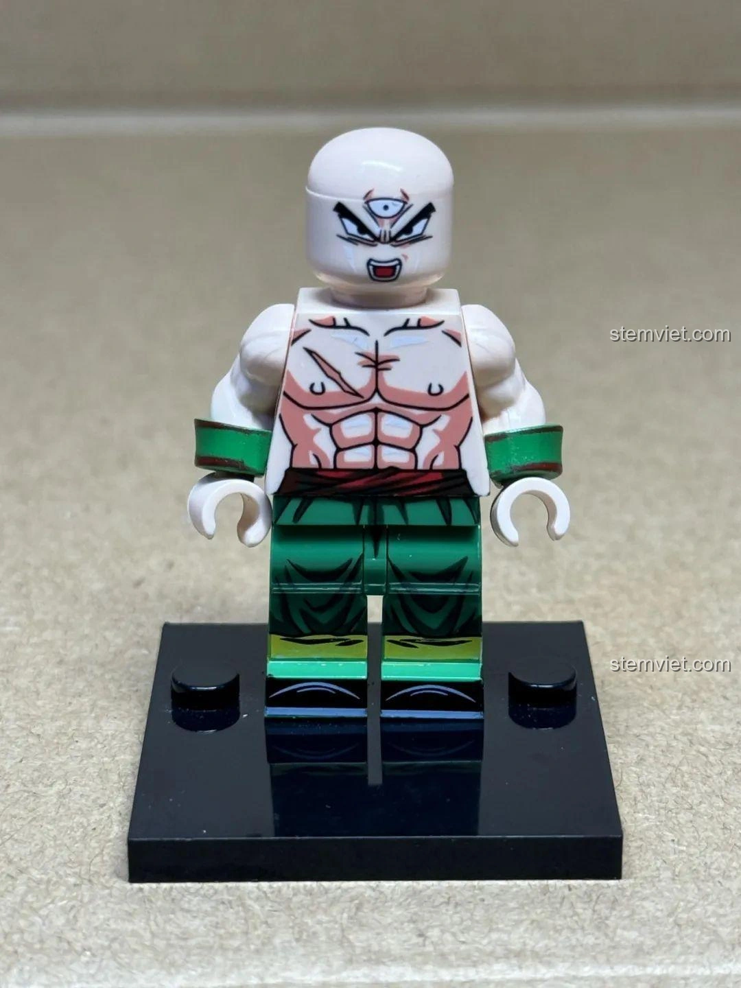 Minifigure Thiên Tân Phạn (Tien Shinhan) trong bộ WM6180 Dragon Ball Z, nổi bật với ba mắt, cơ bắp cuồn cuộn và vết sẹo trên ngực.