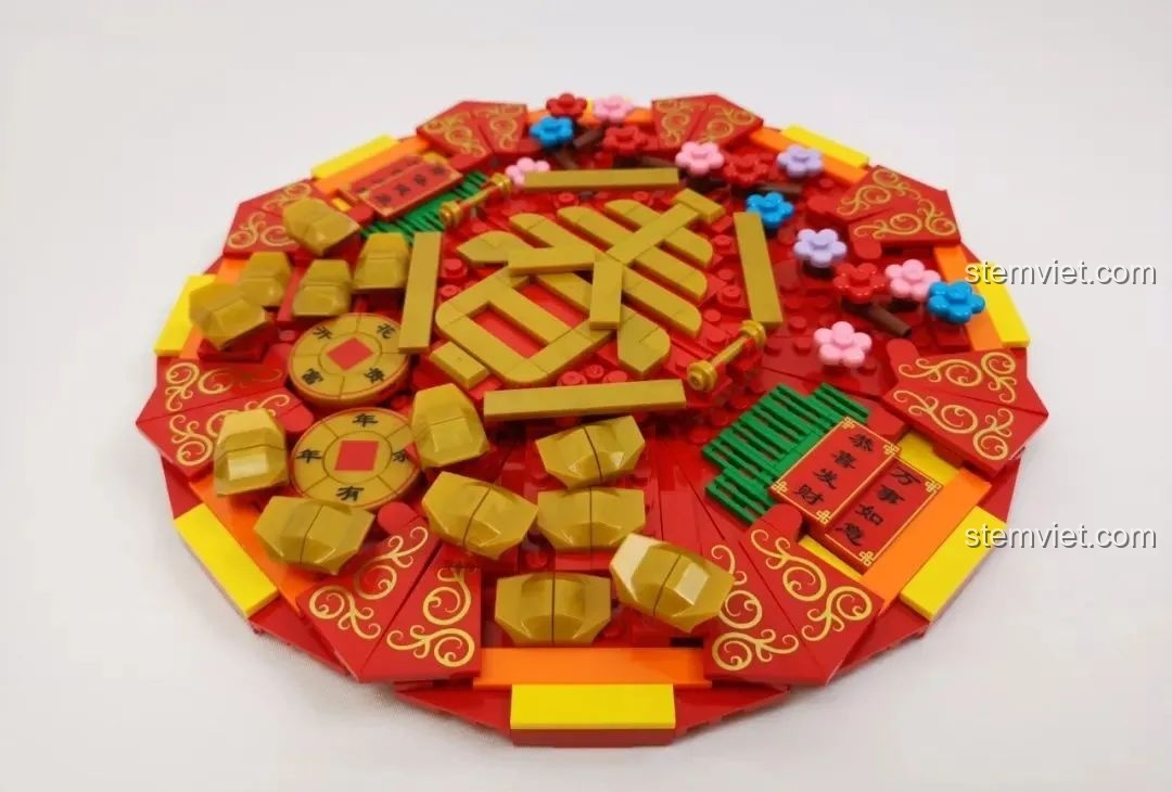 Nắp hộp mứt Tết WOMA C.9122 được trang trí hoàn chỉnh với thỏi vàng và chữ Xuân.