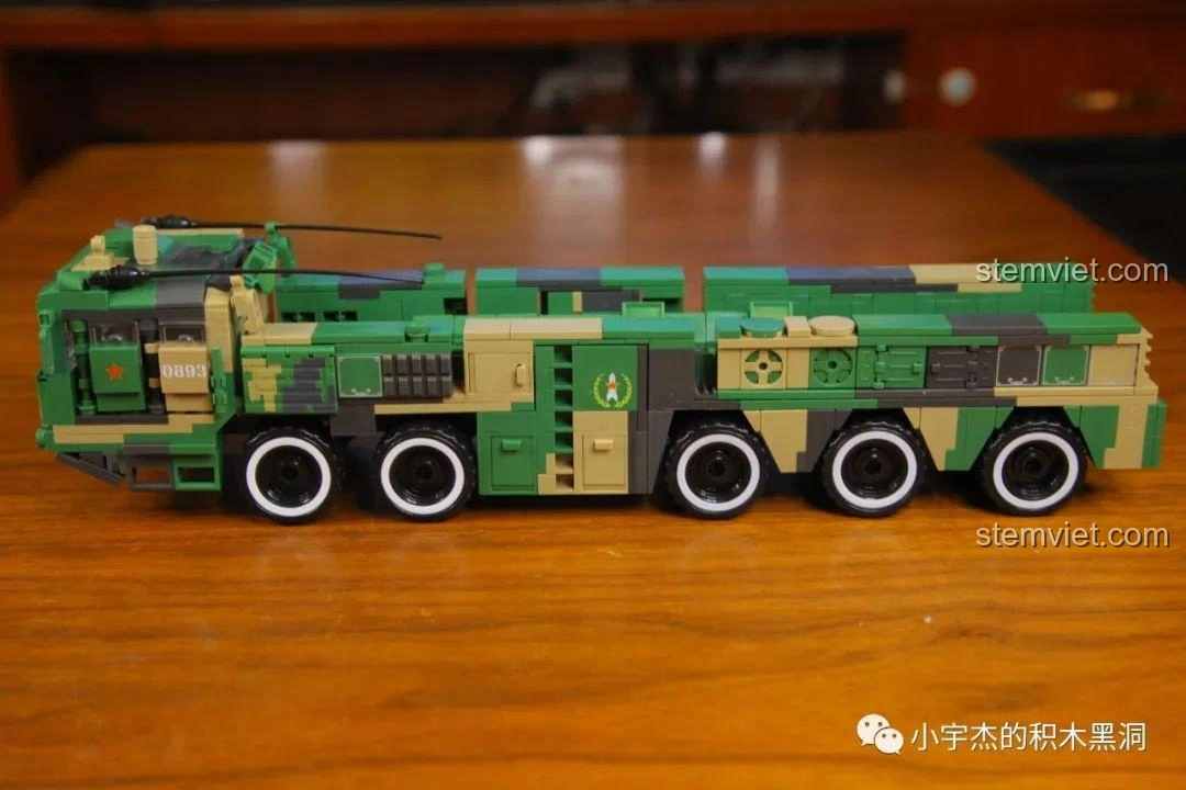 Mô hình xe phóng tên lửa Đông Phong-21D đã hoàn thiện phần thân và bánh xe, sẵn sàng để lắp đặt tên lửa, thể hiện rõ thiết kế ngụy trang pixel.