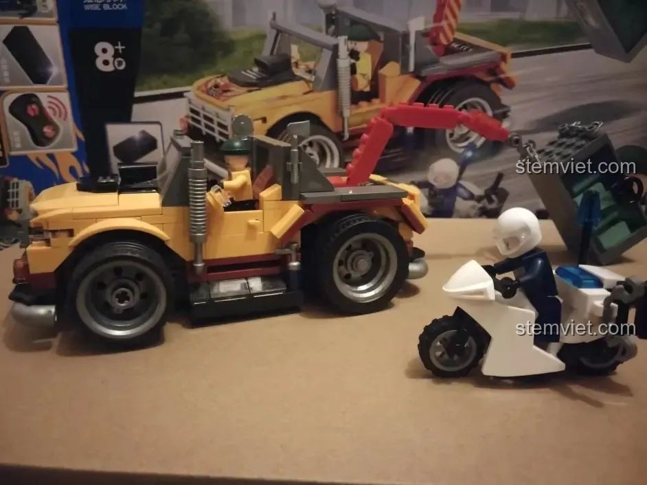 Cảnh sát trên mô tô truy đuổi chiếc xe cứu hộ chở két sắt trong bộ đồ chơi Xe Cảnh Sát Cứu Hộ Điều Khiển Từ Xa HA389120.