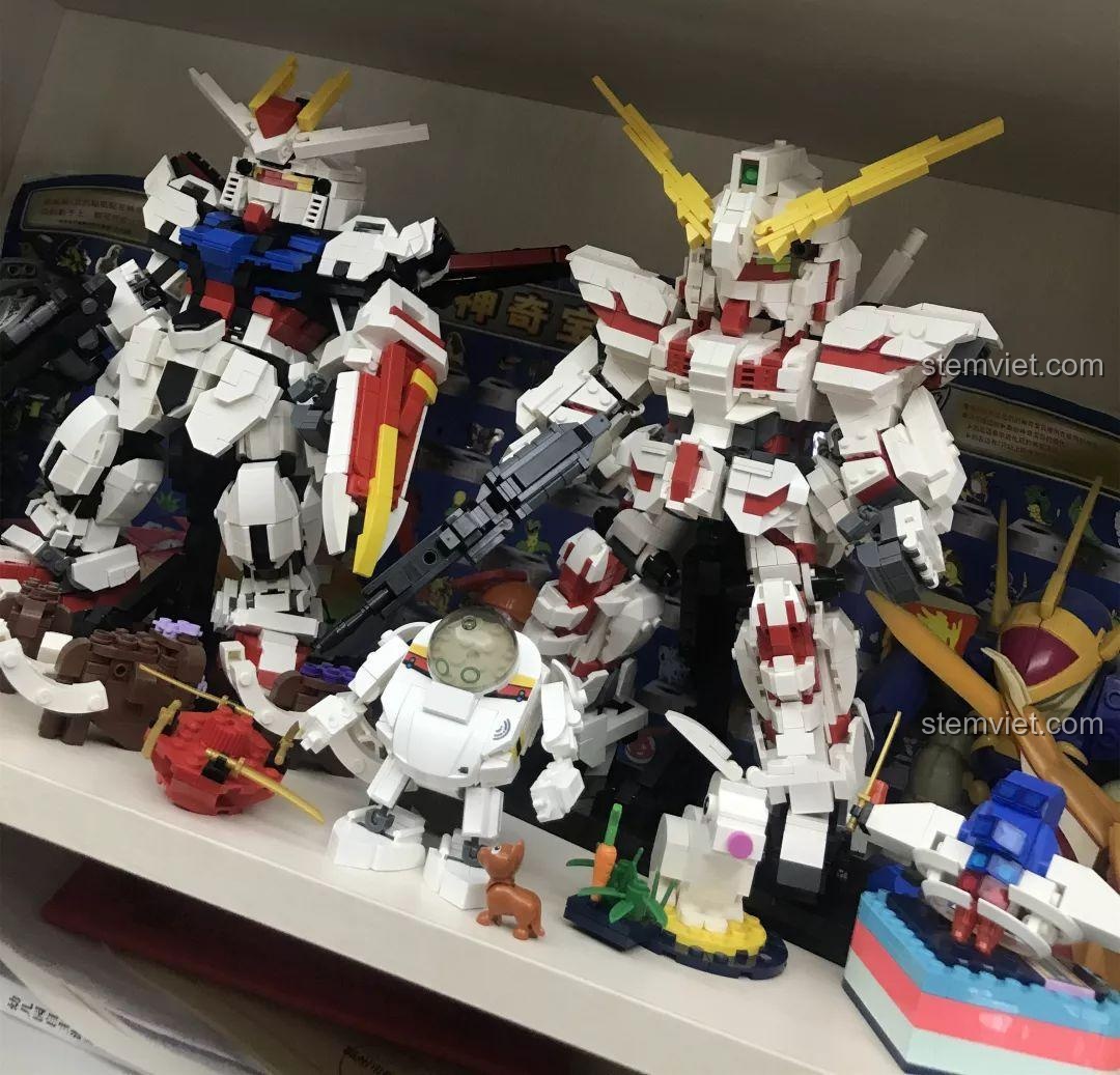 Robot Q-Bricks Sluban M38-B0761E được trưng bày cùng các mô hình Gundam và đồ chơi lắp ráp khác trên kệ. Nhận xét Sluban M38B0761E Robot Q-thông minh.