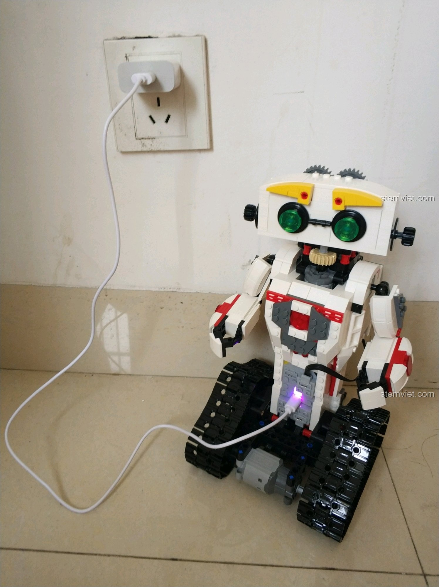 Robot KAKA C51027 đang được sạc pin qua cổng USB, đèn báo hiệu sáng lên, sẵn sàng để hoạt động.