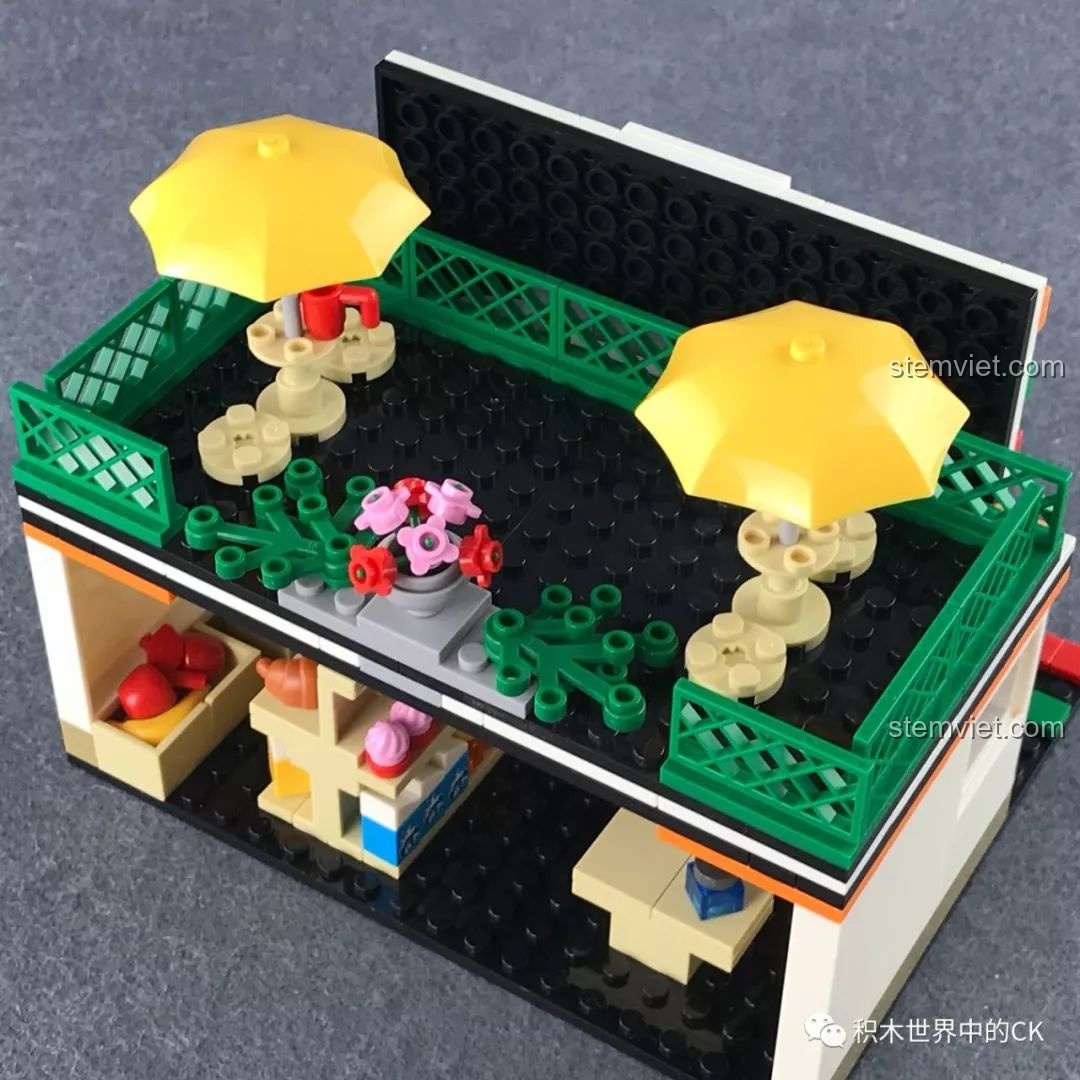 Khu vực sân thượng tầng hai với bàn ghế, dù che và chậu hoa, một phần trong trải nghiệm SEMBO 601017 Cửa hàng tiện lợi 7-Eleven.