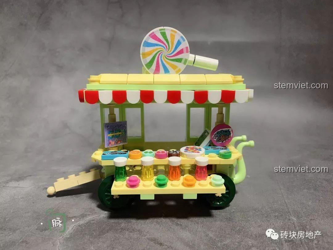 Chi tiết xe bán kẹo mút Sembo 601112, một phần của bộ 4 Xe Đẩy Bán Hàng Rong Mini, với kẹo mút xoắn ốc và các lọ kẹo nhỏ.