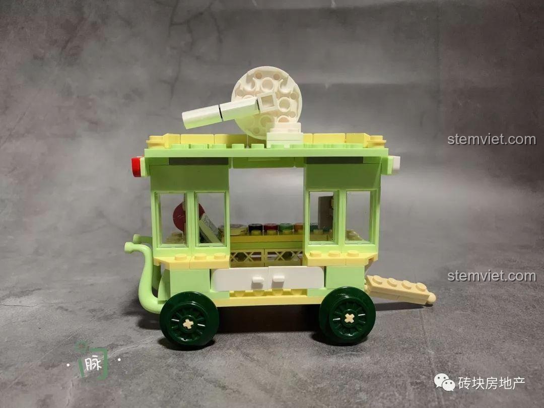 Góc nhìn bên hông xe bán kẹo mút Sembo 601112, thể hiện màu sắc xanh lá cây và mái che sọc đỏ trắng.