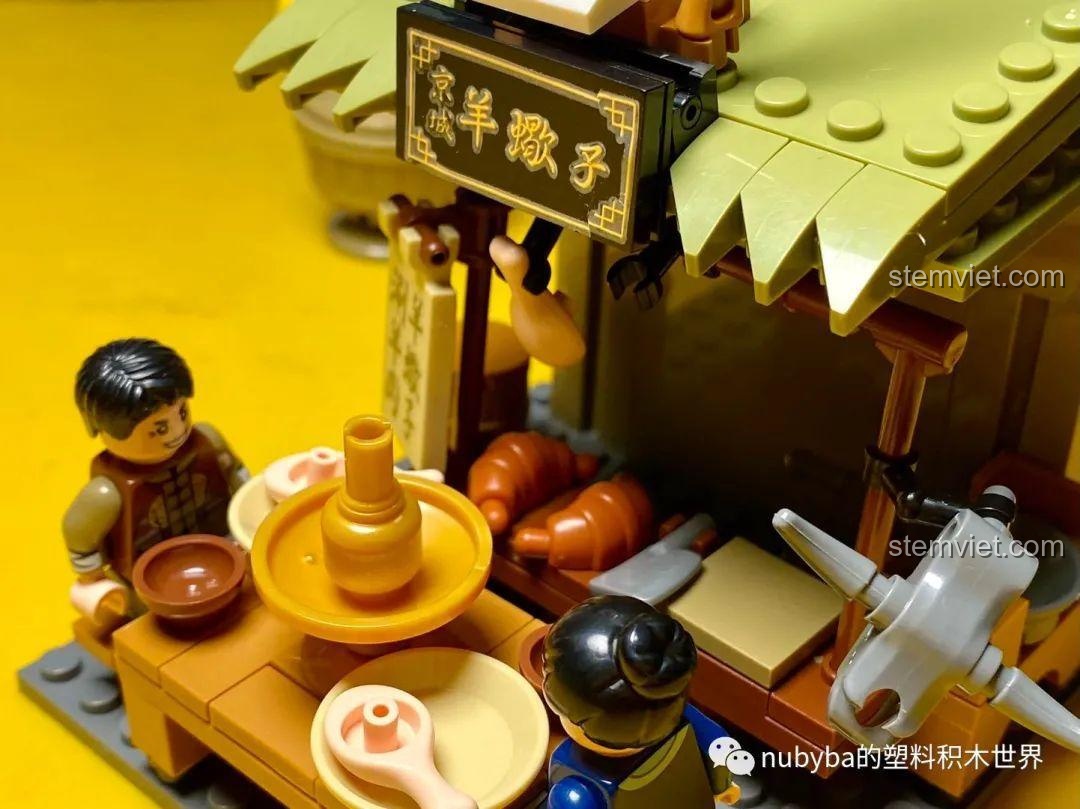 Cận cảnh bàn ăn trong mô hình Cửa hàng lẩu dê xương Bắc Kinh, với nồi lẩu và các món ăn.