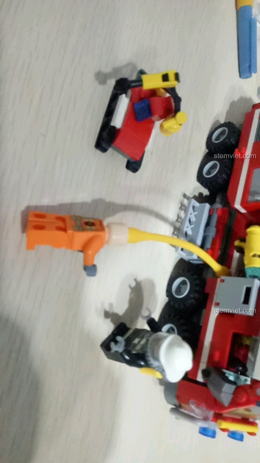 Minifigure lính cứu hỏa đang gắn vòi rồng vào người trong kịch bản cứu hỏa của bộ SEMBO 603034.