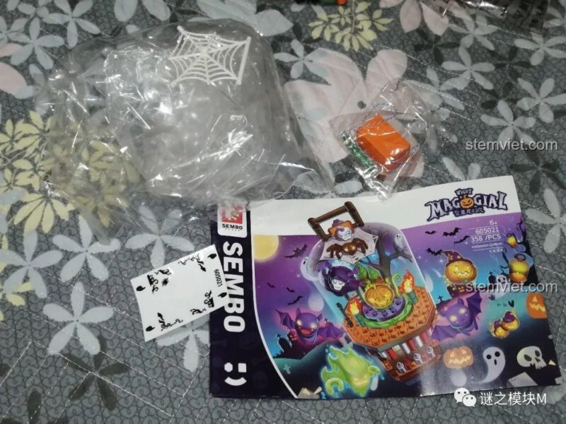 Các bộ phận trong hộp bộ lắp ghép Đèn Lồng Halloween Sembo 605021, bao gồm sách hướng dẫn và các mảnh trong suốt.