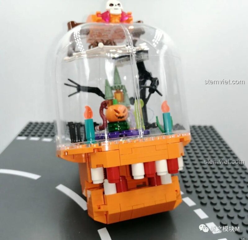 Cận cảnh cảnh quan bên trong đèn lồng của bộ lắp ghép Đèn Lồng Halloween Sembo 605021, với lâu đài, bí ngô và nến.