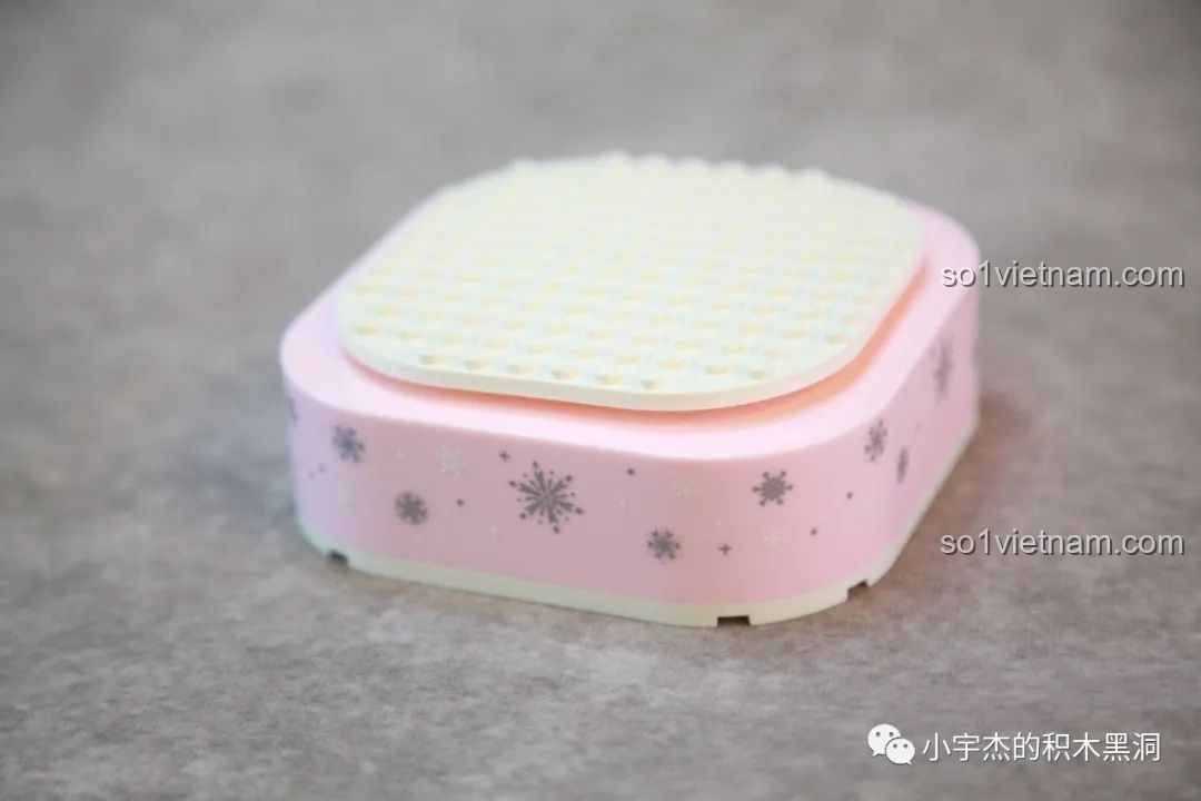 Đế hộp nhạc màu hồng đã được dán sticker bông tuyết, chuẩn bị cho việc lắp ráp Cây Thông Noel Pha Lê SEMBO 605024.