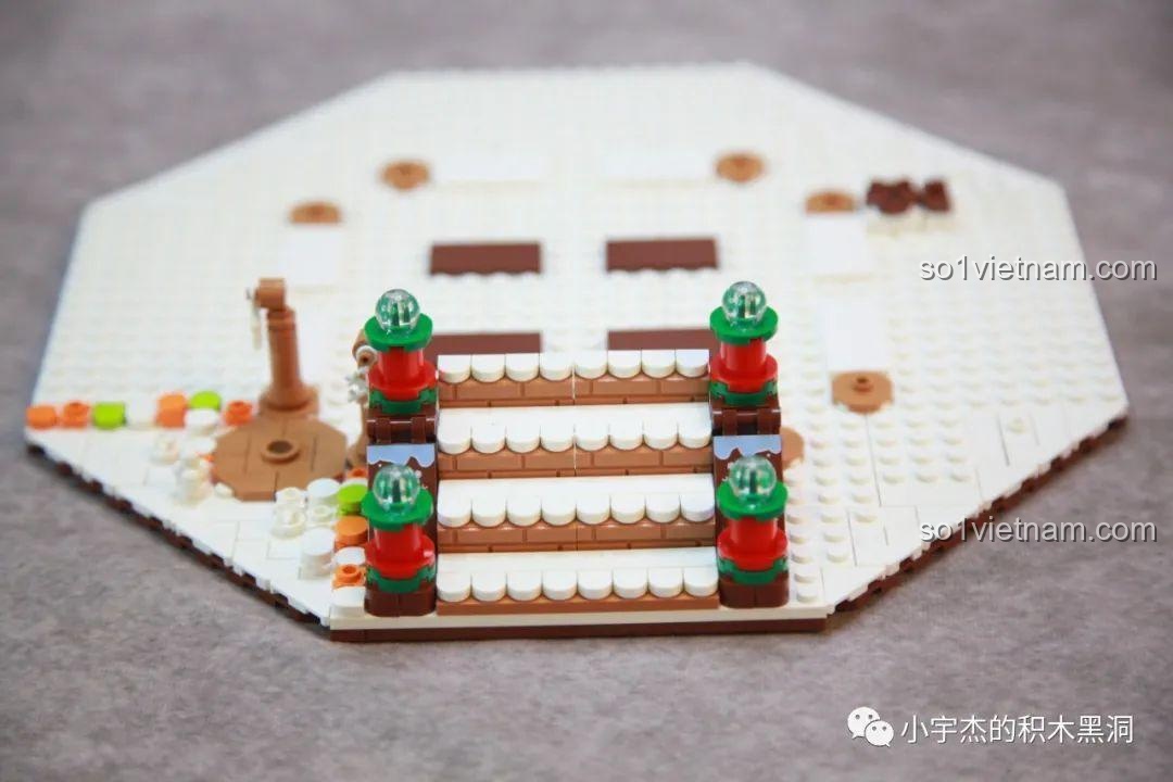 Cận cảnh các bậc thang và chi tiết trang trí trên phần đế của bộ Cây Thông Giáng Sinh Nhạc Hội SEMBO 605025, với các mảnh ghép in.