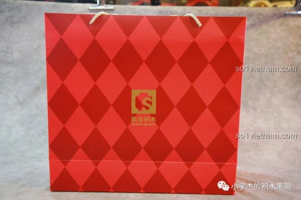 Túi giấy màu đỏ rực rỡ với logo SEMBO, dùng để đựng bộ lắp ráp Cây Thông Giáng Sinh Nhạc Hội SEMBO 605025, rất phù hợp làm quà tặng.