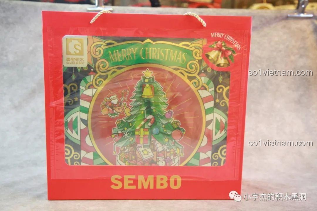 Mặt bên của túi giấy quà tặng SEMBO 605025 có phần trong suốt, hé lộ hộp sản phẩm Cây Thông Giáng Sinh Nhạc Hội bên trong, tạo sự tò mò.