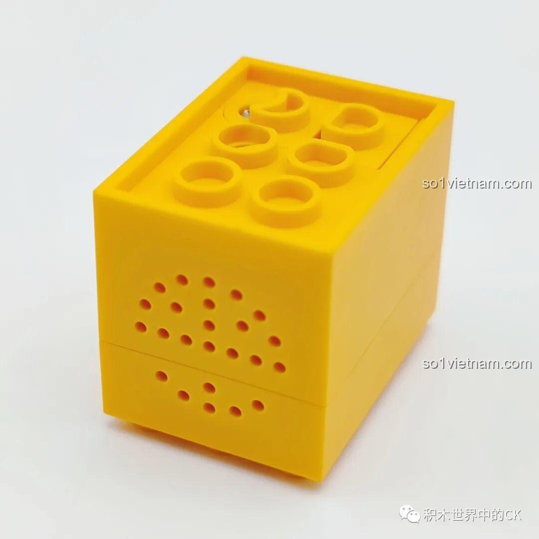 Mặt sau của hộp nhạc màu vàng trong bộ lắp ráp SEMBO 605026 Bó Hoa Giáng Sinh, với các lỗ thoát âm hoặc đèn.