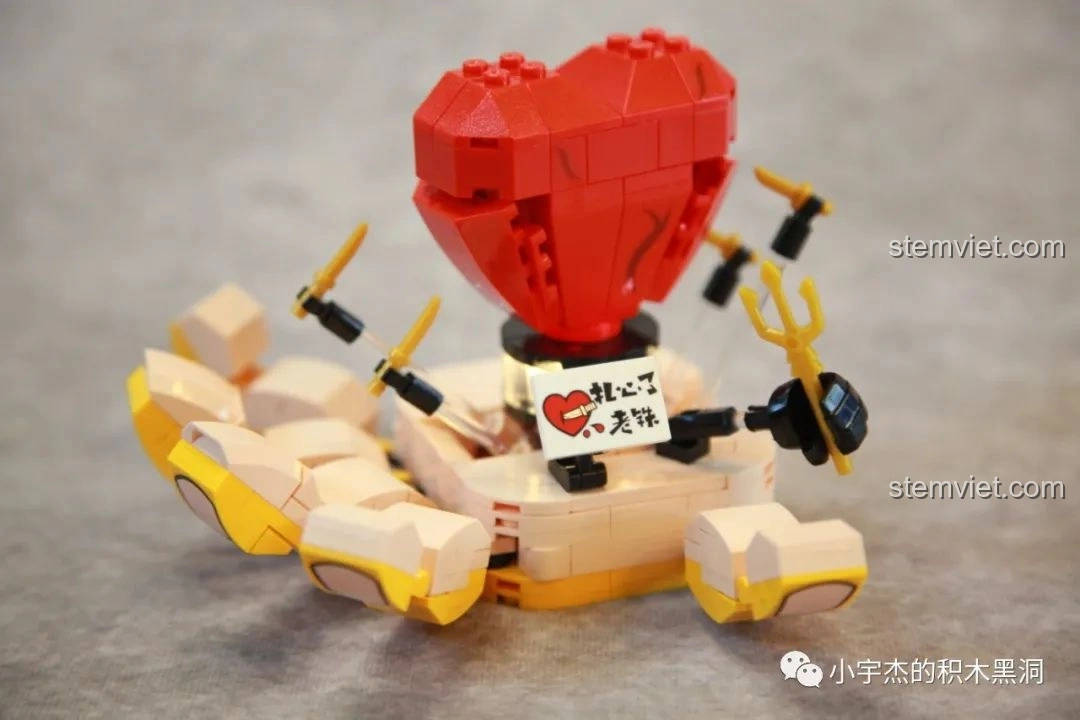 Góc nhìn nghiêng của mô hình Trái Tim Tan Vỡ SEMBO 613105 Hài Cảnh Tinh Linh, cho thấy cơ chế núm xoay điều khiển các thanh kiếm đâm xuyên trái tim. Tính năng tương tác độc đáo.