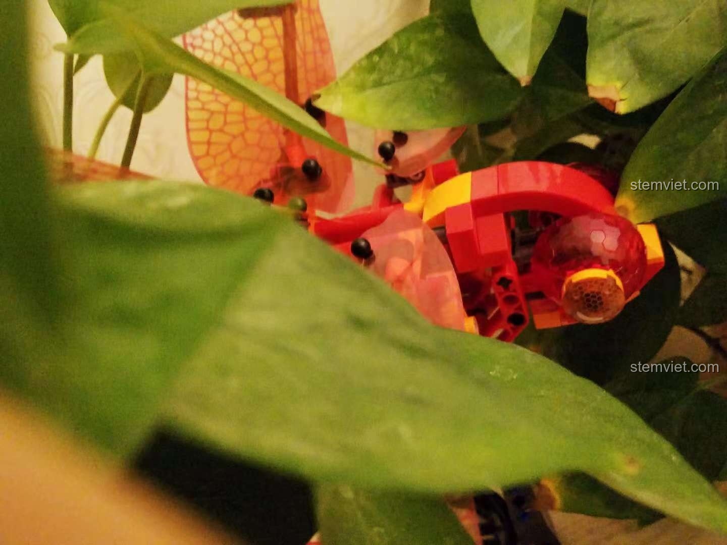 Cận cảnh đồ chơi mô hình Sembo 703300 Chuồn Chuồn Đỏ Cơ Khí giữa tán lá, chi tiết tinh xảo.
