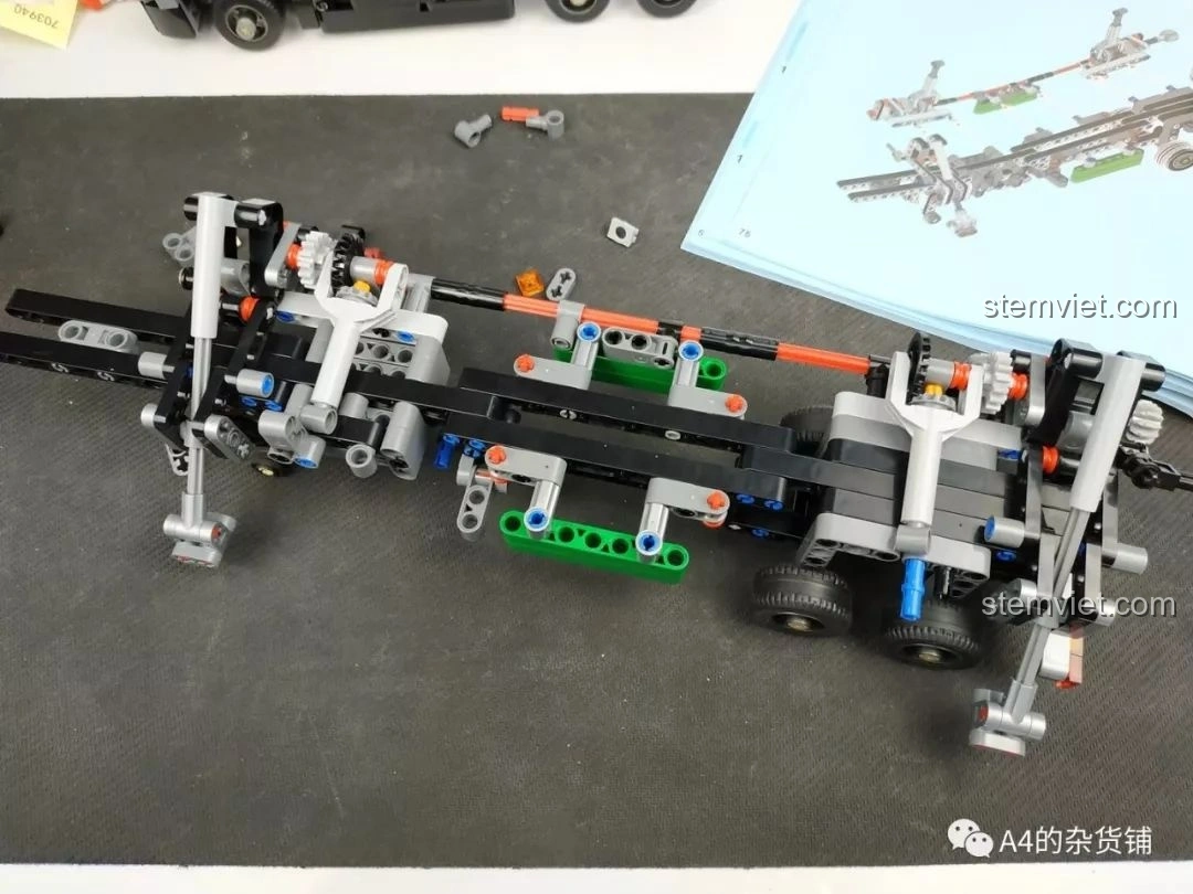 Phần khung gầm xe tải với cơ cấu hỗ trợ (chân chống) đã hoàn thiện, với các chi tiết Technic màu đen, xám và xanh lá, của bộ lắp ráp Xe Tải Container Cơ Khí SEMBO 703940.