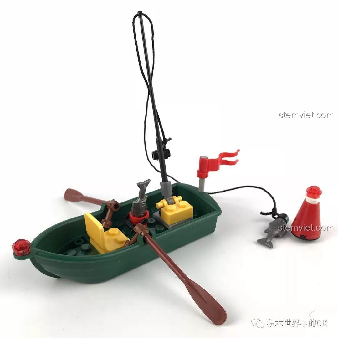 Mô hình thuyền câu nhỏ màu xanh lá cây, có cần câu, mái chèo và một con cá đã câu được.