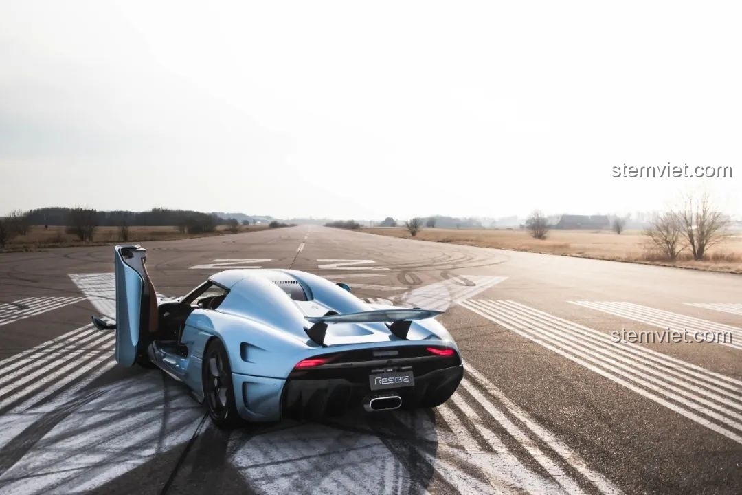 Hình ảnh thực tế của siêu xe Koenigsegg Regera màu xanh trên đường đua, nhìn từ phía sau.