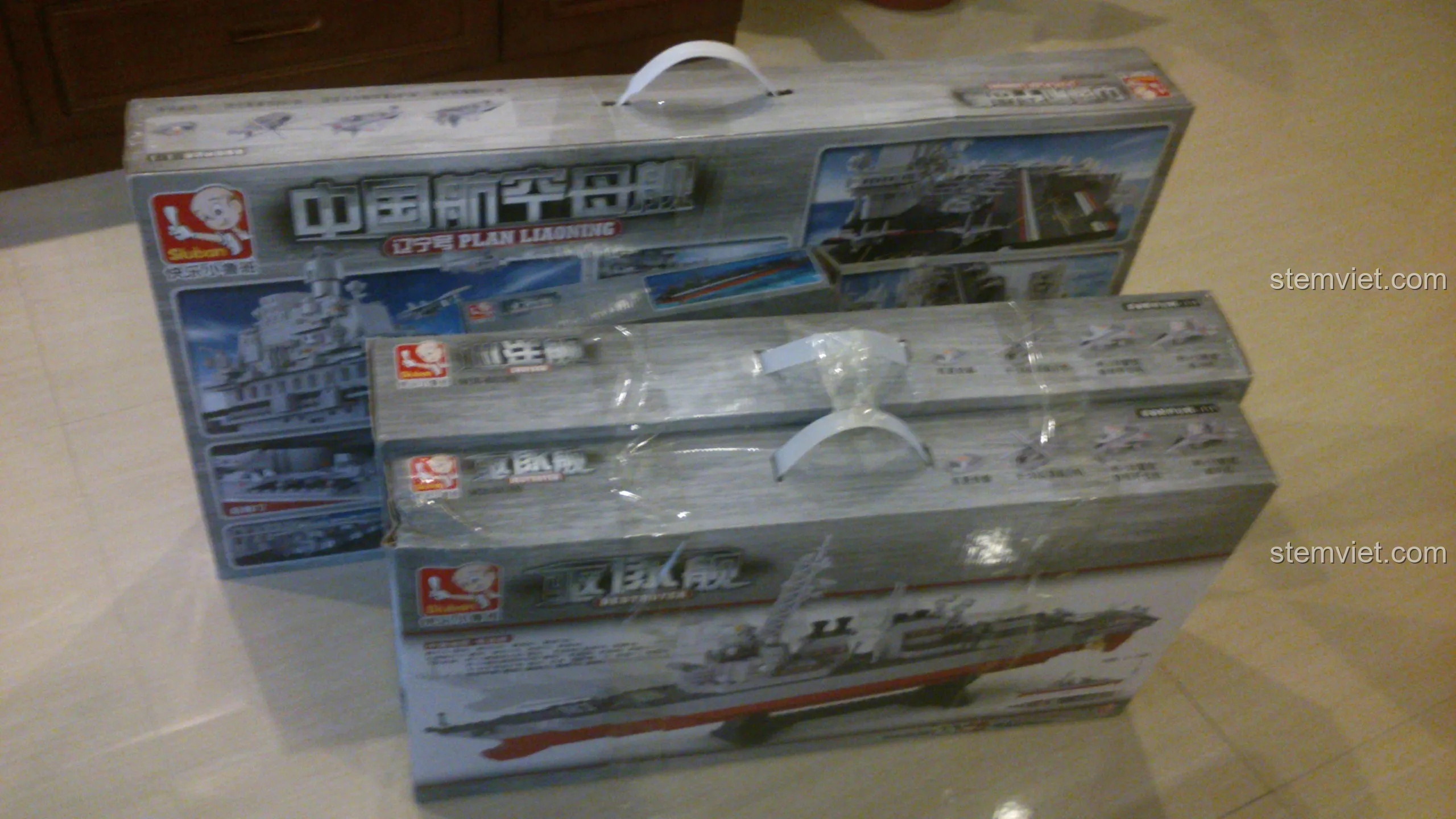 Hai hộp đồ chơi lắp ráp Sluban lớn, một hộp tàu sân bay và một hộp tàu tuần dương, chuẩn bị cho trải nghiệm unboxing.