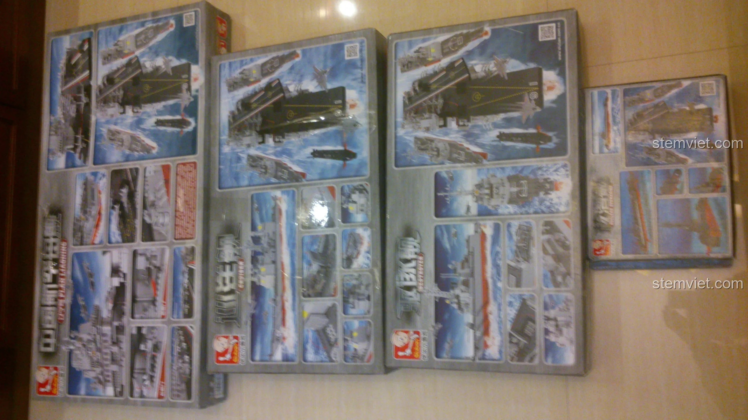 Mặt sau của các hộp đồ chơi lắp ráp Sluban Hàng không mẫu hạm, hiển thị các chi tiết và mô hình đã hoàn thành.