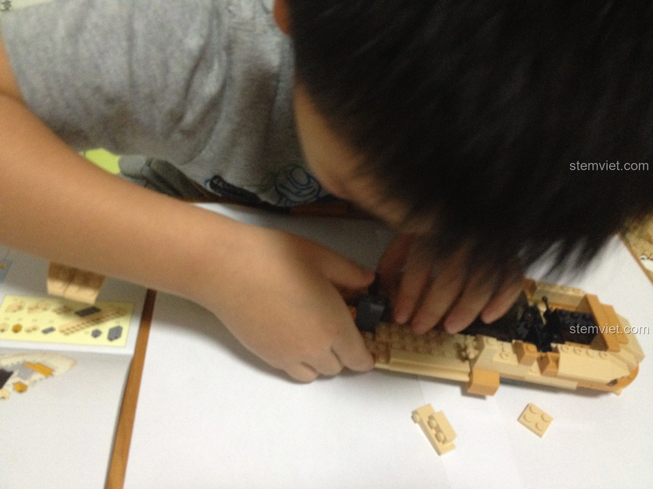 Bé trai nghiêm túc lắp ráp bộ Sluban M38-B0509 Trực thăng Black Hawk UH-60L, thể hiện sự say mê.